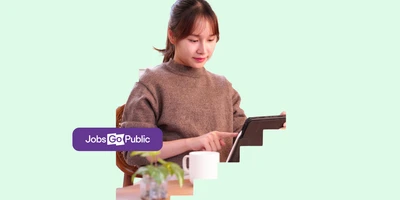 A local government worker in her mid 30s is sitting at a desk using a digital tablet