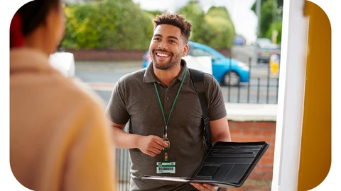A housing officer with a folder is standing in someone's doorway smiling at the resident who is out of shot