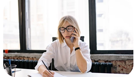 Female solicitor sitting at a table and taking notes while on the phone